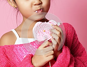 Happy young asian little girl kid lick eat happy big sweet lollypop candy on pink