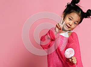 Happy young asian little girl kid lick eat happy big sweet lollypop candy on pink