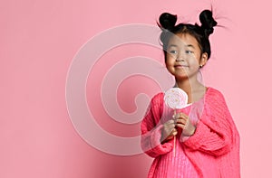 Happy young asian little girl kid lick eat happy big sweet lollypop candy on pink