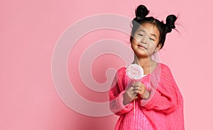 Happy young asian little girl kid lick eat happy big sweet lollypop candy on pink