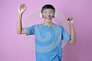 Happy Young Asian man listening to music with wireless headphone and dancing
