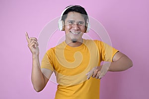 Happy Young Asian man listening to music with wireless headphone and dancing