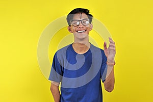 Happy Young Asian man smiling wearing glasses, isolated on yellow