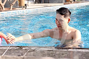 Happy young Asian man swimming in blue water pool, relaxing swimmer male have fun activity in summer. Swimming for exercise, swim