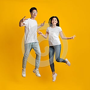 Happy young asian man and woman jumping up while posing