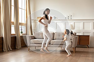 Happy young Asian mom and daughter dancing at home