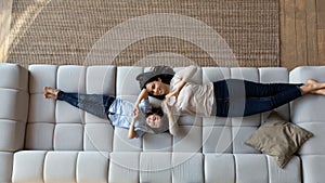 Happy young Asian mom and little son lying on sofa