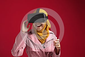 Happy young Asian muslim girl playing on VR glasses. Virtual reality concept, young girl having fun with headset goggles