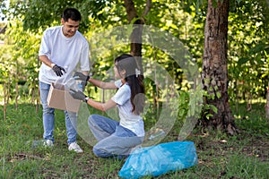 Happy young Asian students diverse volunteers with garbage bags cleaning area in the park, The concept of environmental