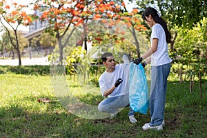 Happy young Asian students diverse volunteers with garbage bags cleaning area in the park, The concept of environmental