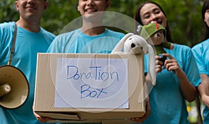 Happy young Asian students diverse volunteers hold donate box and toys for charity to share children and orphanages, a charity for photo