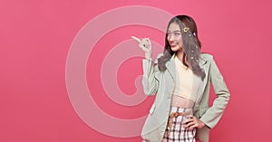 Happy young Asian teen woman standing with her finger pointing isolated on pink background with copy space