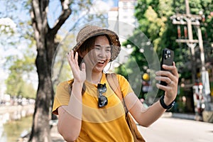 happy young Asian tourist taking picture with a smartphone while visiting a Chinese temple