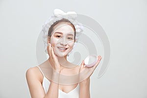 Happy young Asian woman applying facial clay mask and wearing a towel