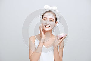 Happy young Asian woman applying facial clay mask and wearing a towel