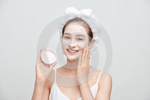 Happy young Asian woman applying facial clay mask and wearing a towel