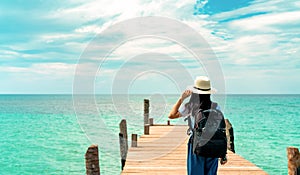 Happy young Asian woman in casual style fashion with straw hat and backpack. Relax and enjoy holiday at tropical paradise beach.