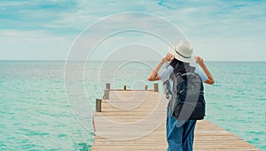 Happy young Asian woman in casual style fashion with straw hat and backpack. Relax and enjoy holiday at tropical paradise beach.