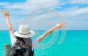 Happy young Asian woman in casual style fashion with straw hat and backpack. Relax and enjoy holiday at tropical paradise beach.