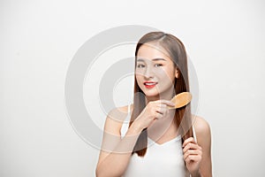 Happy young Asian woman combing her hair