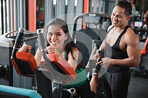 Happy young asian woman doing back leg presses