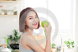 Happy Young Asian Woman Eating Green Apple on Kitchen. Diet. Die