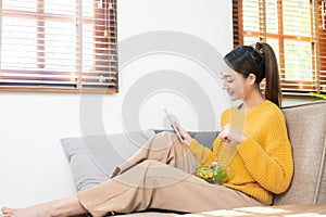 Happy young Asian woman with fresh vegetables and fresh fruits, healthy concept working lunch at home,
