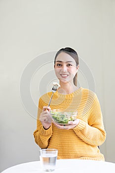 Happy young Asian woman with fresh vegetables and fresh fruits, healthy concept working lunch at home,