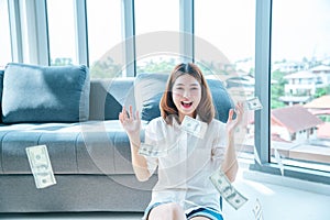 Happy young asian woman holding dollar money and throw in the air celebrate happiness dance wealth lottery money rain drop. Winner