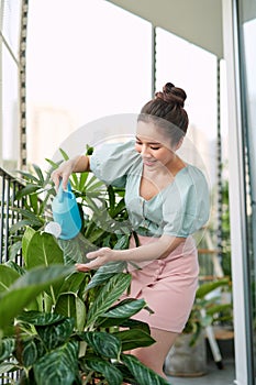 Happy Young Asian Woman housewife Watering flowers On Balcony