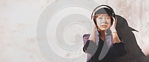 Happy young asian woman listening to music with headphones on the street. Banner background.