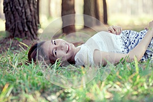 Happy young asian woman lying down on grass