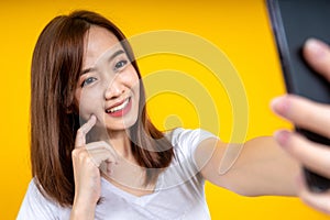 Happy young Asian woman posing isolated over yellow wall background