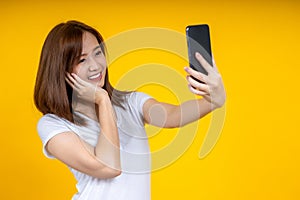 Happy young Asian woman posing isolated over yellow wall background