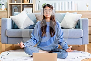 Happy young Asian woman practicing yoga and meditation at home sitting on floor in living room