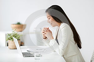 Happy young asian woman reading good online news on laptop