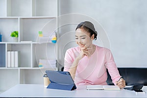 Happy young Asian woman relaxing at home sitting on sofa and using mobile smartphone using social media,