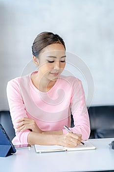 Happy young Asian woman relaxing at home sitting on sofa and using mobile smartphone using social media,