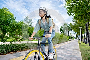 Happy young Asian woman while riding a bicycle in a city park. She smiled using the bicycle of transportation. Environmentally