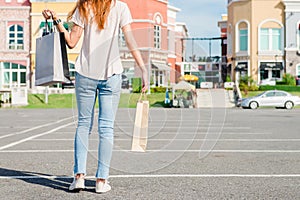 Happy young Asian woman shopping an outdoor market with a background of pastel buildings and blue sky.