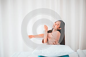 Happy young asian woman stretching and waking up in her bedroom at home in the morning