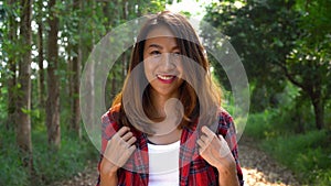 Happy young Asian woman traveler with backpack walking in forest.