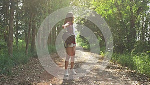 Happy young Asian woman traveler with backpack walking in forest. Hiker Asian woman with backpack walking on path in summer forest