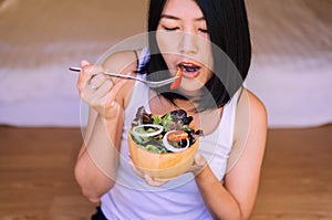 Happy young asian woman using fork eating breakfast salad for healthy,Selective focus