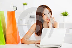 Happy young asian woman using a laptop with bags.
