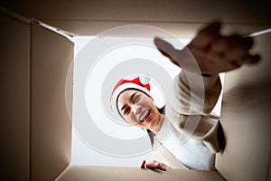 Happy young asian woman wearing christmas hat and unpacking gift box