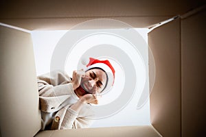 Happy young asian woman wearing christmas hat and unpacking gift box