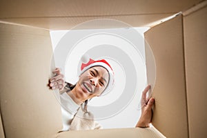 Happy young asian woman wearing christmas hat and unpacking gift box