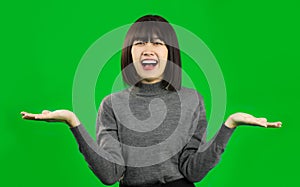 Happy Young Asian woman wearing gray shirt posing like show something on green screen