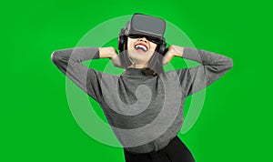 Happy Young Asian woman wearing a gray shirt and a VR headset, greenscreen